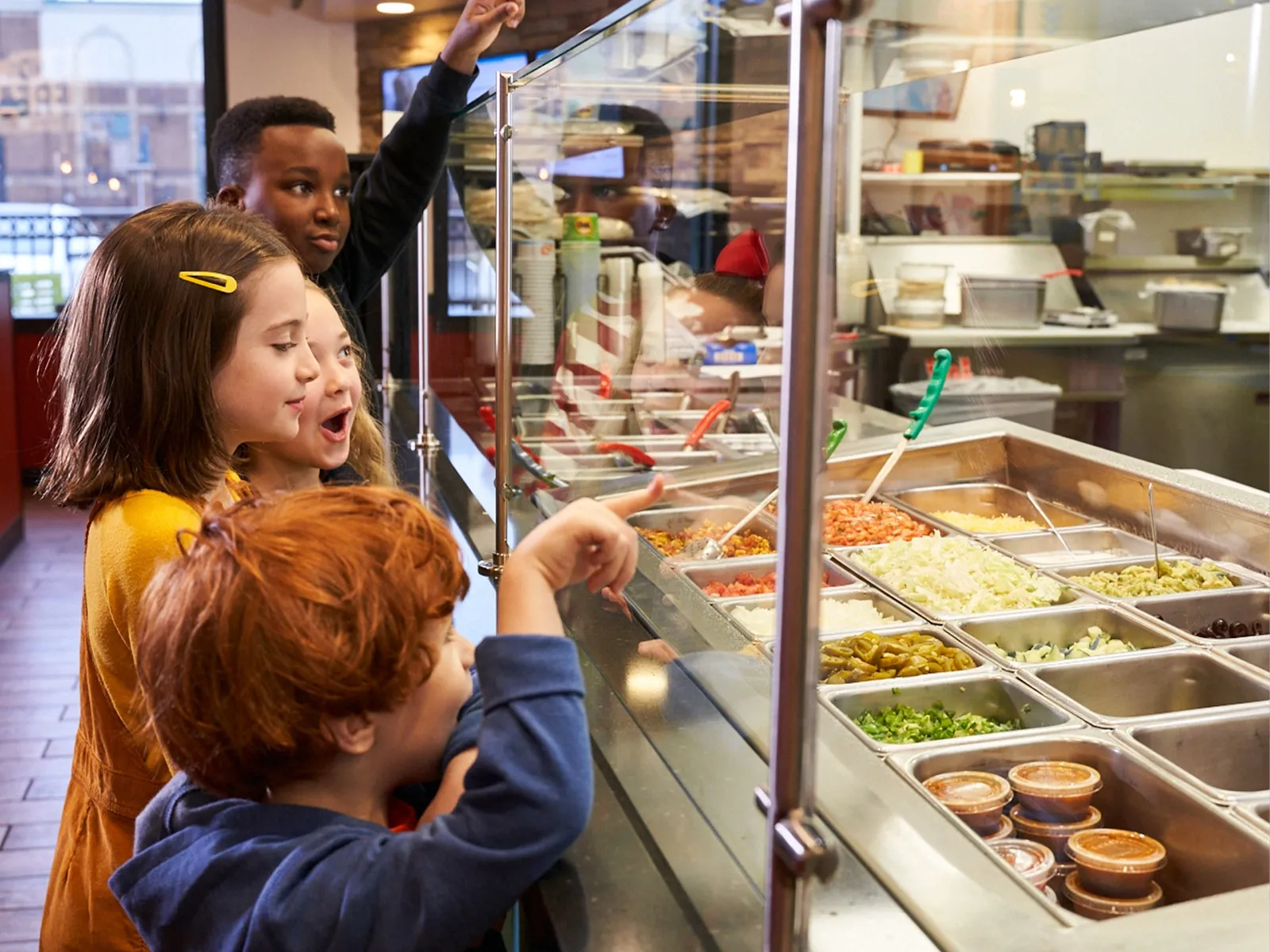 Kids choosing toppings at the Moe's toppings bar